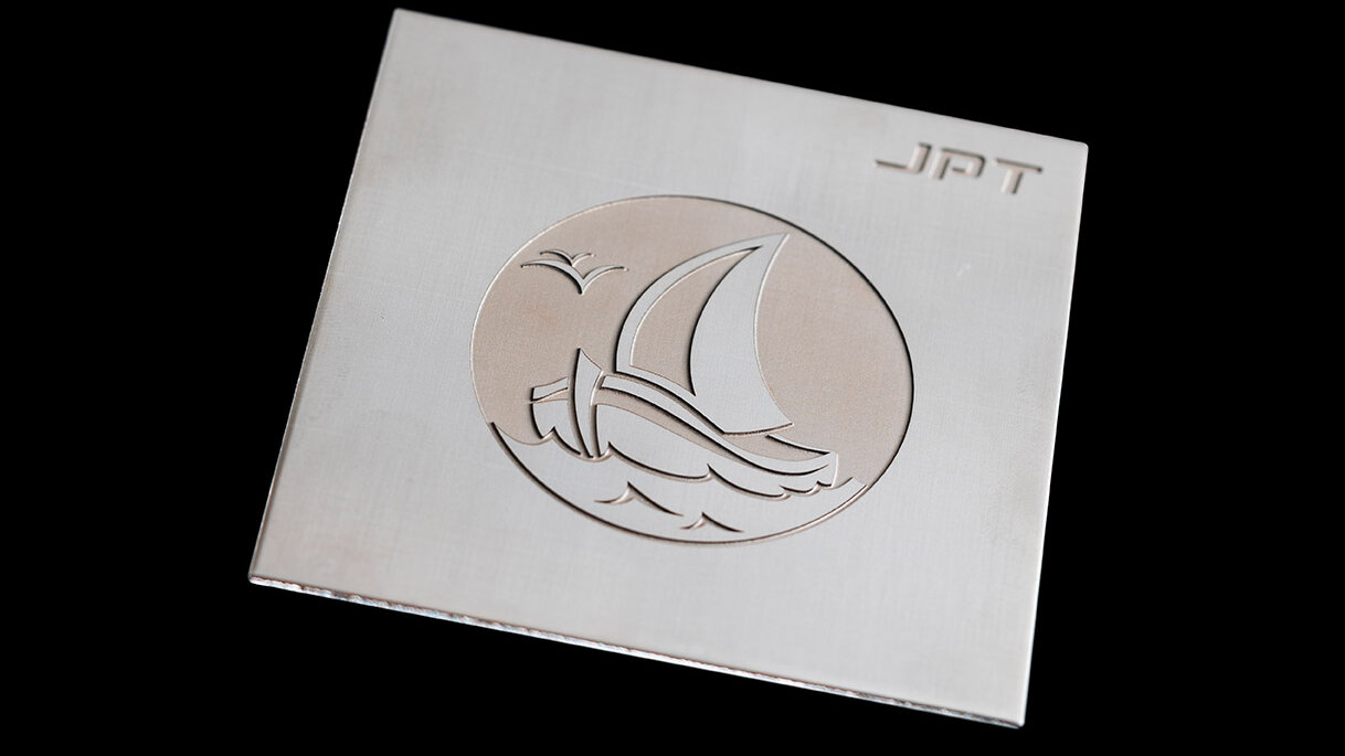 A boat sailing across the sea on a stainless steel plate engraved with a laser.