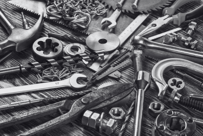 Viele verschiedene Werkzeuge auf einem Tisch, die den Maschinenbau und die Werkzeugindustrie symbolisieren.