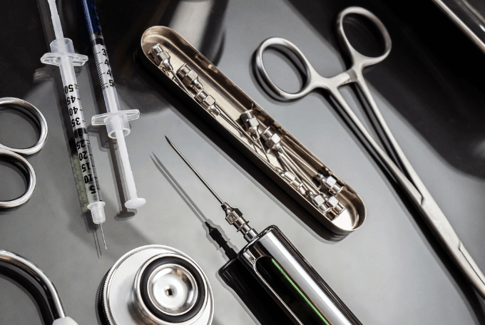 Verschiedene medizinische Instrumente auf einem schwarzen Tisch, die die Medizintechnik symbolisieren. 