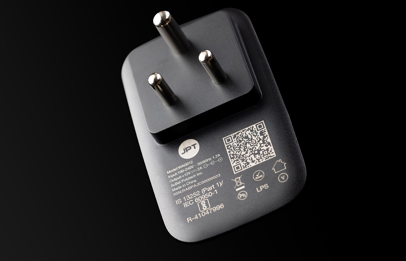 White barcode laser marking on a black plastic charging plug.