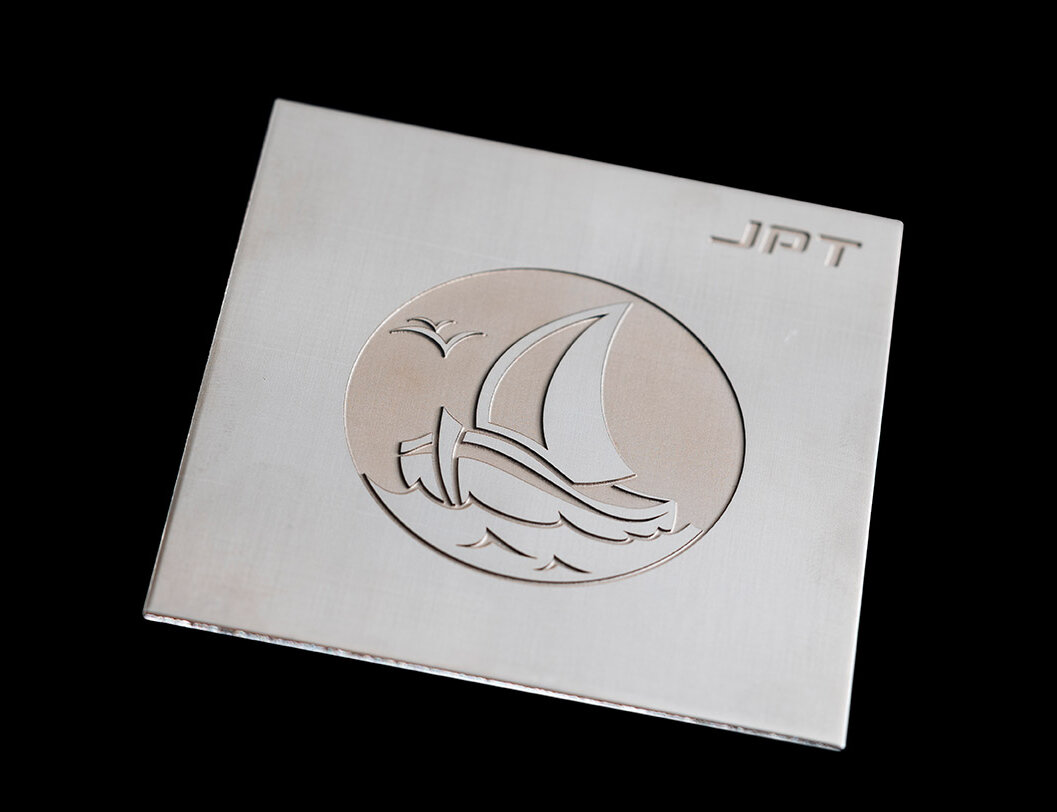 A boat sailing across the sea on a stainless steel plate engraved with a laser.